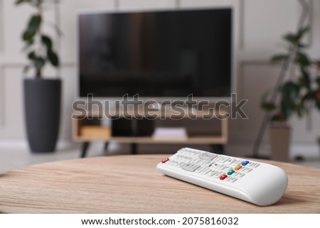 Wooden cabinet with modern TV indoors, focus on remote control