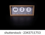 A wooden calendar block showing the date August 21st on a dark black background, save the date or date of event concept