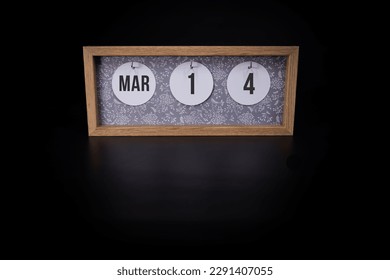A wooden calendar block showing the date March 14th on a dark black background, save the date or date of event concept.
