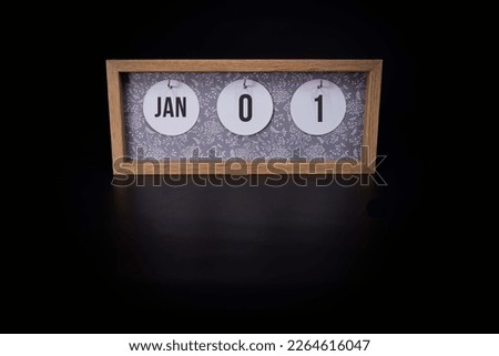 A wooden calendar block showing the date January 1st on a dark black background, new years day concept calendar reminder for the 1st of January which is the first day of the year