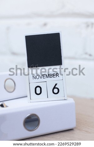 Wooden calendar with date November 06 against brick wall background. Deadline, planning, business concept