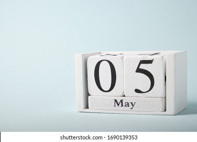 Wooden calendar on a blue background with the date of May 5