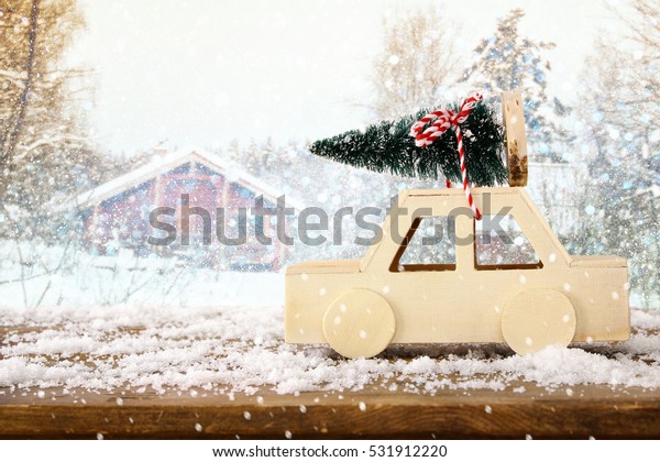 Wooden car carrying a\
christmas tree in front of dreamy and abstract magical winter\
landscape\
\
