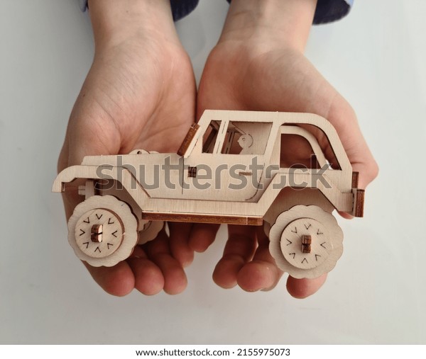 Wooden car in children hand\
protection safety and insurance. Ecological toys for children\
concept