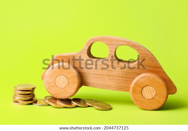Wooden car with coins\
on color background