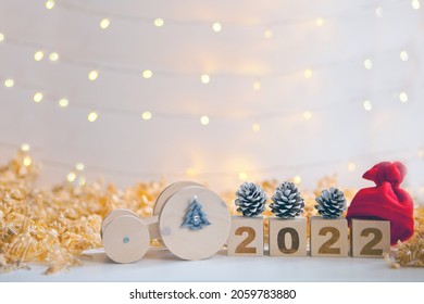 wooden car driving new year numbers 2022, red hat and pine cones. toy car carrying timber blocks. Happy new year celebration and Christmas approach. Lights and copy space - Powered by Shutterstock