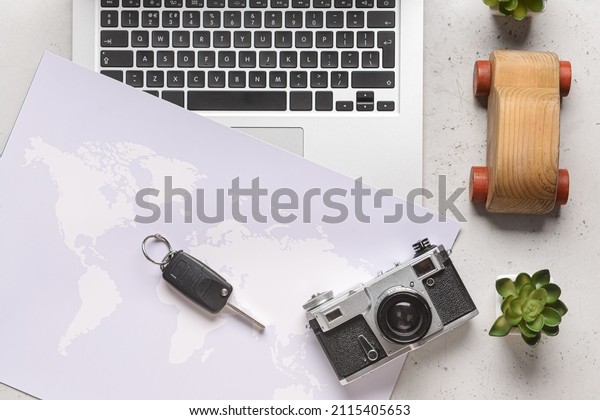Wooden car with laptop, map, key and photo\
camera on light\
background