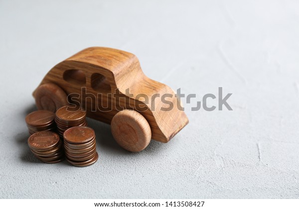 Wooden car\
model and coins on table. Space for\
text