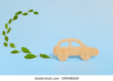 Wooden Car Model Emitting Fresh Green Leaves On Blue Background. Sustainable, Clean And Green Energy And Biofuel And Biodiesel For Transportation Industry Concept.