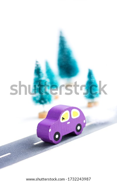 Wooden car on paper road against\
fir-trees on white background. Traffic on country road.\
Travel