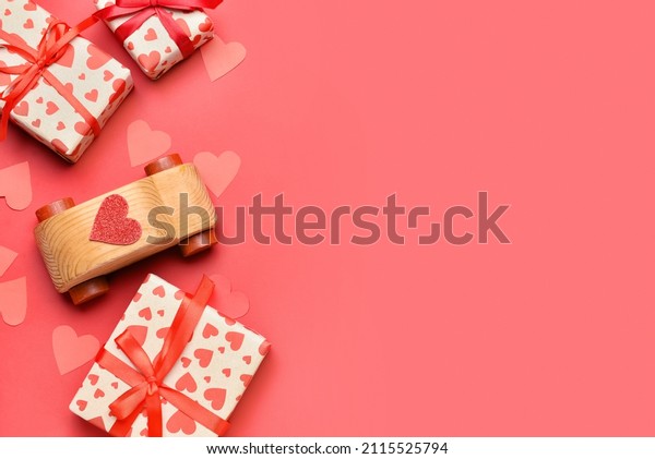 Wooden car with paper hearts and gift\
boxes on red background. Valentine\'s Day\
celebration