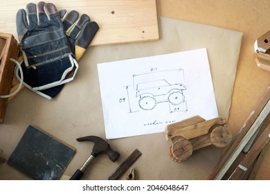 Wooden Car Toy And Drawing Design On Table In The Workshop, DIY Wood Work, Wooden Plank In Background, Concept Of DIY, View From Above