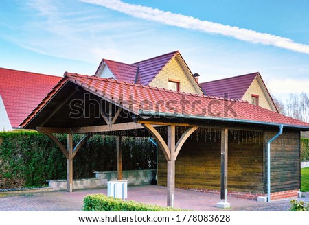 Wooden carport with red brick roof on a new house.