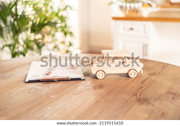 The wooden car\'s\
model and documents on the desk. Insurance details, car rental.\
Safe Vehicle Concept.  \
\
