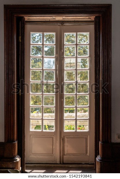 Stock photo of old glass doors leading to bright sunlit garden