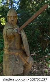 A wooden carved sculpture of an 11th Century soldier with armour, sword and shield at Battle Abbey in East Sussex, UK.  Battle Abbey is on the sight of the 1066 Battle of Hastings battlefield. 