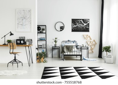 Wooden Chair At Desk With Laptop In Workspace In Monochromatic Boy's Bedroom With Carpet, Round Clock And Plants