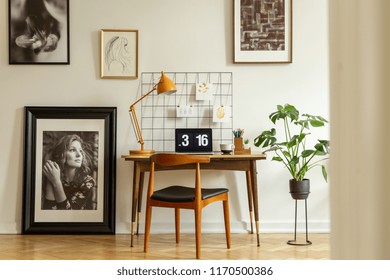 Wooden Chair At Desk With Yellow Lamp And Laptop In Home Office Interior With Gallery. Real Photo