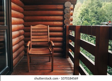 Wooden Chair On Porch Of Cabin Among Woods. Cottage Balcony With View On Forest In Mountains. Atmospheric Moment. Summer Vacation. Rural Country Relax Time