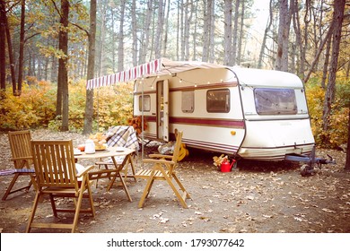 Wooden chairs and table with tea set placed outside cozy retro caravan on autumn day in peaceful countryside - Shutterstock ID 1793077642