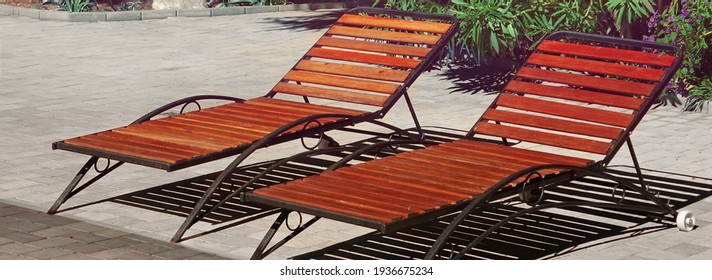 Wooden Chaise Lounges Or Sunbeds In Garden Patio At Pool. Wooden Deck Chairs Or Plank Beds On Concrete. Sunbeds On Backyard.