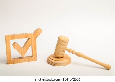 A wooden checkmark and a hammer of the judge on a white background. referendum and elections. Appointment of a judge, election to a constitutional court. Control over the government elections. - Shutterstock ID 1144842626