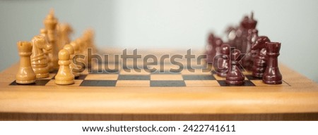 A wooden chess board with hand carved, wooden chess pieces. Pieces are Dark Brown and Light Brown.