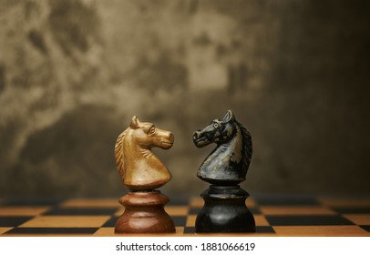 Wooden chess pieces knights facing each other on a vintage chessboard. Confrontation and rivalry concept, selective focus. - Shutterstock ID 1881066619