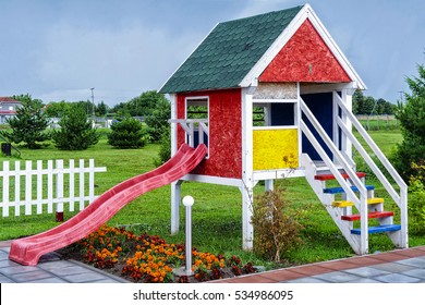 Wooden Children Playhouse With Slides In Backyard Spring Garden 