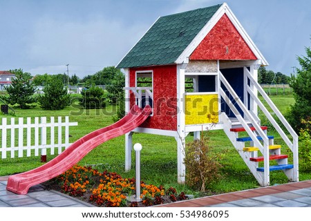 wooden children playhouse with slides in backyard spring garden 