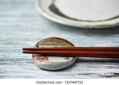 Wooden chopsticks, chopstick rest and empty ceramics plate on rustic wooden background. Close up. Copy space.  - Powered by Shutterstock