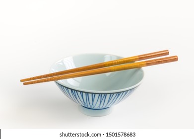 Wooden chopsticks with empty ceramic bowl on white background.
