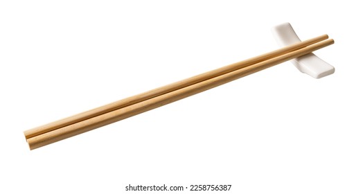 Wooden chopsticks on a white chopstick rest cutout. Pair of bamboo chopsticks on a porcelain holder  isolated on a white background. Japanese, Chinese, East Asian tableware concept. Top view.