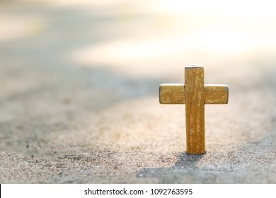 Wooden Christian cross on concrete floor with blurred background. Christianity Concept. Faith hope love concept.