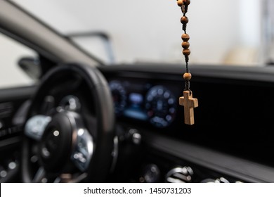 Wooden Christian rosary with crucifix hanging on car rear mirror.