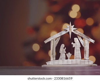 A wooden Christmas Nativity set with the holy family gazing at baby Jesus with a bokeh background.