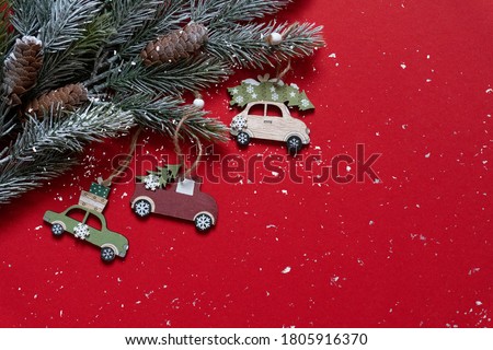 Wooden Christmas and new year toys on Christmas tree branches on the high corner on red background with snow, top view, copy space, banner, holiday mood.