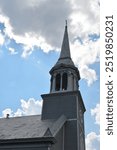 Wooden church steeple reaching up into clouds and sun