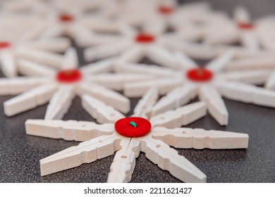 Wooden clothespin in the form of a snowflake with a red button,  close-up. Preparation of DIY crafts, handmade and creative, inspiration.