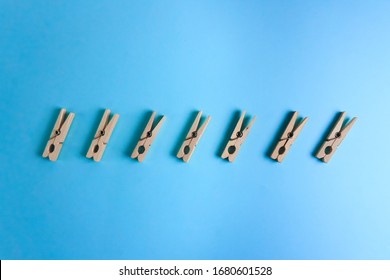 wooden clothespins lie in a row on a blue background.Household items for drying clothes.
