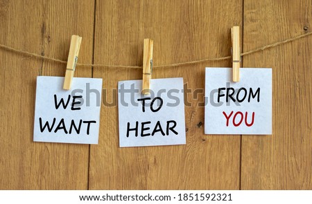 Wooden clothespins with white sheets of paper. Text 'we want to hear from you'. Beautiful wooden background. Business concept, copy space.