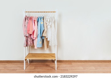 Wooden Clothing Rack With Children's Dresses, Sweaters And Jacket In Kids Room. Montessori Wardrobe. Nursery Storage Ideas. Baby Girl Clothes.	