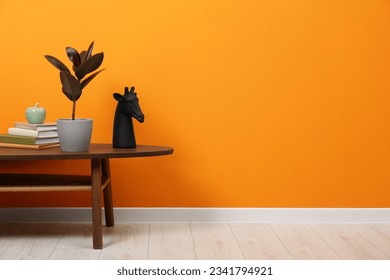 Wooden coffee table with different decor near orange wall indoors, space for text. Stylish interior design - Powered by Shutterstock