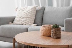 Holzkaffeetisch Mit Hauspflanze Und Korbkorb In Der Nähe Von Grauem Sofa Im Wohnzimmer
