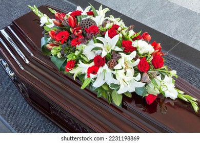Wooden coffin with a beautiful arrangement of flowers on the lid. Funeral ceremony and farewell. Close-up. Top view.