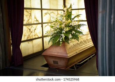 Wooden Coffin With Funeral Flowers In Crematorium