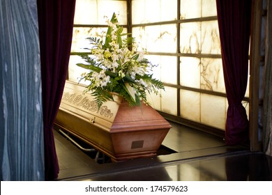 Wooden Coffin With Funeral Flowers In Crematorium