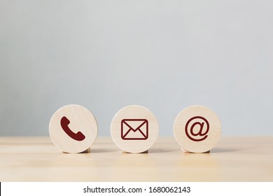 Wooden coins with symbol telephone, email, address. Website page contact us or e-mail marketing concept