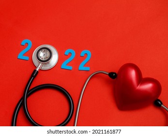 Wooden colorful on text 2022 banner for health care and Red heart love medical concept. black stethoscope,on table red background.