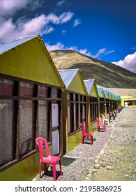 Wooden Colorful Row House At The Bank Of Pangong Lake. Lake And House In The Lap Of Mountains And Deep Blue Sky With Clouds.